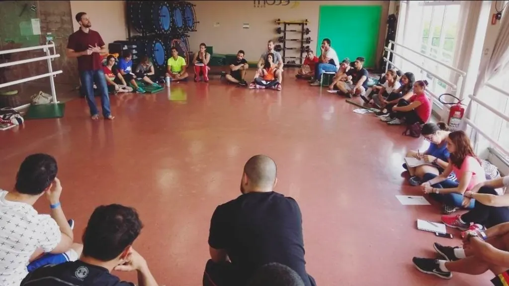 Pedro Emerson conduzindo aula presencial com turma sentada em círculo